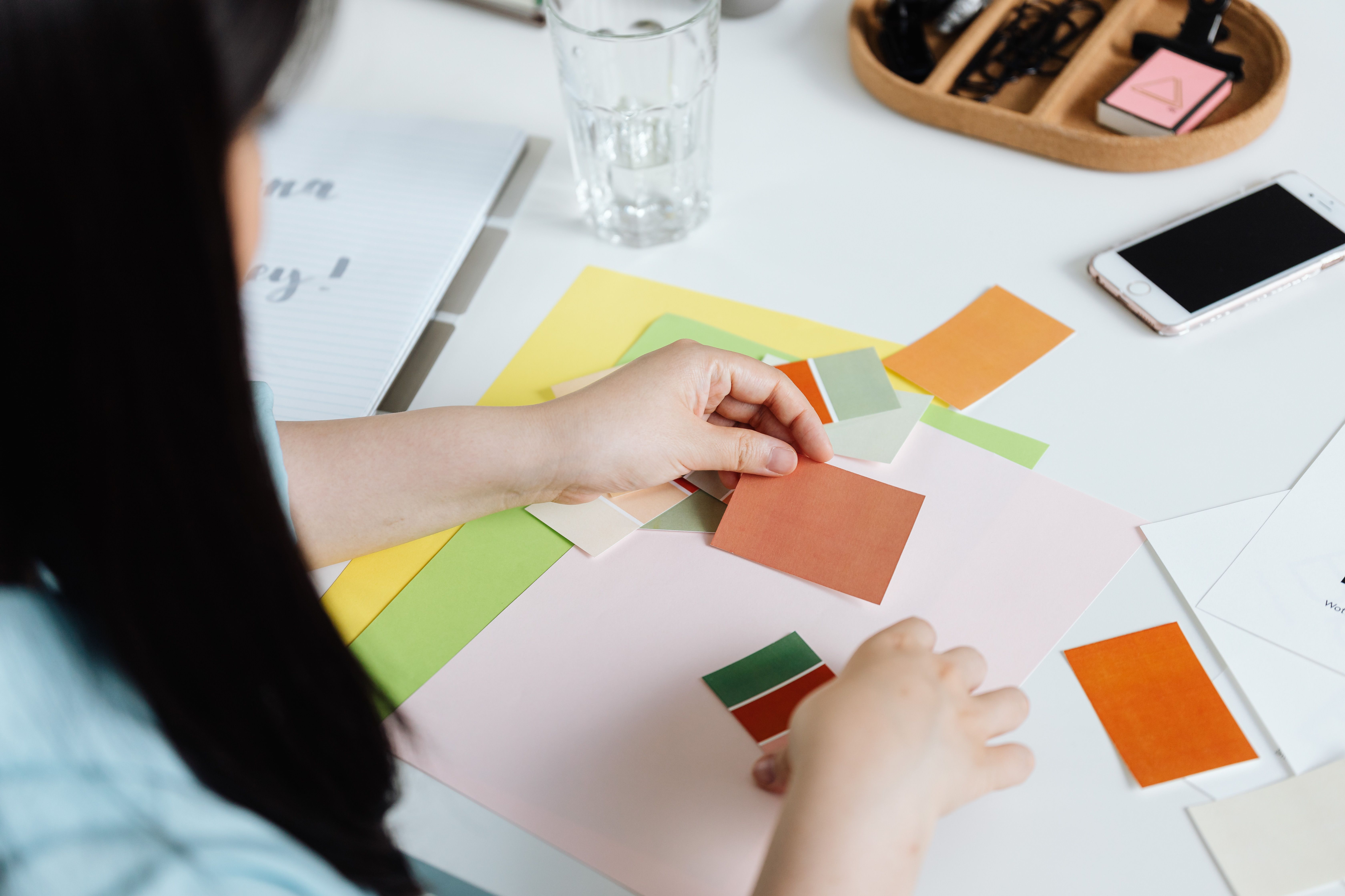 Hands arranging colour swatches and papers on a creative work table